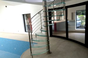 Designer glass spiral staircase with stainless steel balustrade ultra clear glass stair treads in a swimming pool Leeds1