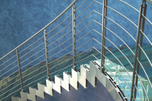 Curved modern and contemporary glass staircase with stainless steel zig zag sides and traversal rod balustrade Curved modern and contemporary glass staircase with stainless steel zig zag sides and traversal rod balustrade